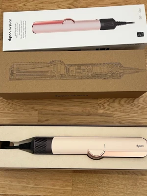 Dyson AirStrait rosa hårstyler - Säljer en Dyson AirStrait hårstyler i snygg ljusrosa och silver design. Perfekt för att styla och torka håret samtidigt. Ergonomisk form och modern look, levereras i originalförpackning. Passar dig som vill ha ett innovativt stylingverktyg från Dyson.