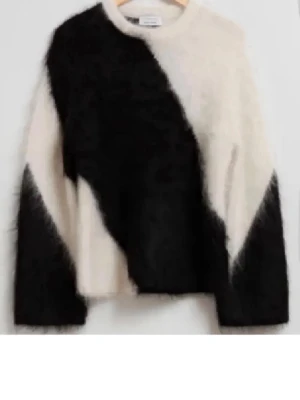 Stickad tröja med svartvit diagonal design - Säljer en fluffig stickad tröja i svart och vitt med en cool diagonal färg-design. Tröjan har rund halsringning och långa ärmar. Materialet är nått slags mohair eller liknande.