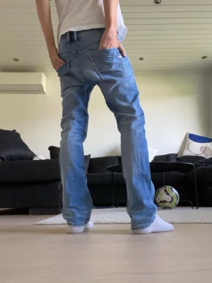 Ljusblå raka jeans med slitningar - Säljer ett par ljusblå jeans från diesel med raka ben och slitna detaljer på framsidan. Jeansen har klassiska fem fickor och normal midja. Perfekta för en avslappnad och trendig stil. Materialet är denim i bomull.