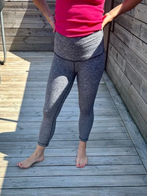 Lululemon Gråmelerade träningstights med hög midja - Säljer ett par gråmelerade träningstights med hög midja och åtsittande passform. Tightsen är stretchiga och perfekta för gymmet, yoga eller löpning. Materialet är mjukt och följsamt, vilket ger bra rörelsefrihet. Trekvartslöngd. Väldigt sköna! 