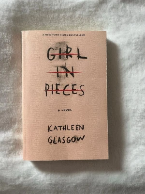 Girl in Pieces av Kathleen Glasgow - Girl in Pieces av Kathleen Glasgow är en roman med ett beige, matt omslag och svart handskriven text. Boken har ett minimalistiskt och konstnärligt uttryck med titeln överstruken i rött. Perfekt för dig som gillar starka berättelser om tonårsliv och känslor.