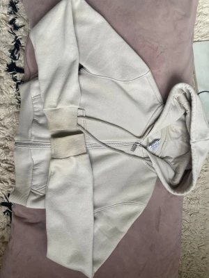 Gripbar beige zip-hoodie  - Snygg croppad beige hoodie med dragkedja. Klassisk modell med huva och ribbade muddar vid ärmar och midja. Väldigt mjukt material. Lite missfärgad vid toppen av armarna och är lite nopprig som bilderna visar. Pris kan diskuteras.