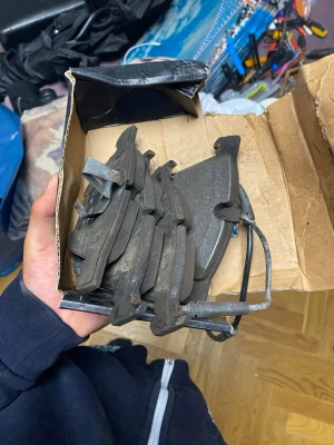 Bromsbelägg till bil i kartong BMW f10 - Säljer ett gäng bromsbelägg till bil, levereras i en enkel kartong. Beläggen är svarta och har metallfästen. Perfekt för dig som behöver reservdelar till bilen. Inga märkningar synliga på produkten.