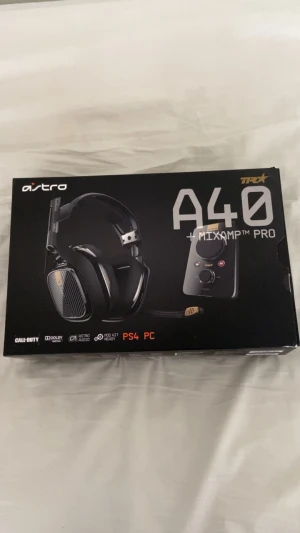 Astro A40 + MixAmp Pro gamingheadset - Astro A40 TR headset med MixAmp Pro, perfekt för gaming på PS4 och PC. Svart design med detaljer i silver och guld, justerbar mikrofon och stora öronkåpor. kan glappa Levereras i originalförpackning med tydliga funktioner för ljudkontroll och anpassning.