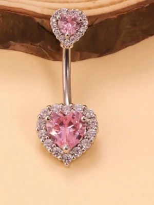 Navelpiercing med rosa hjärtan rostfrittstål - Snygg navelpiercing i silverfärgad metall med rostfrittstål med två hjärtformade rosa stenar, omgivna av små gnistrande klara stenar. Perfekt för dig som vill ha en söt och glittrig detalj till din look. Hjärtana ger en romantisk vibe och smycket har en elegant böjd stav.