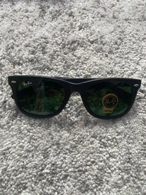 Ray-Ban Solglasögon - Ett par svarta Ray-Ban solglasögon i nytt skick, oanvända. Orginalförpackning, etui med mera medföljer självklart (se bild 5). Hör gärna av er om det är nåt ni undrar!