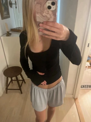 Svart långärmad croppad topp - Säljer en svart, croppad topp med lång ärm och djup, rundad urringning. Toppen har en tight passform och är perfekt att styla med både jeans och kjol. Materialet känns mjukt och stretchigt. Ställ gärna frågor om ni undrar något!💞