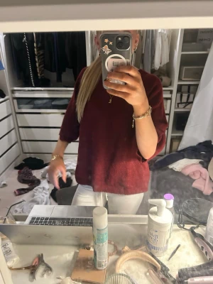 Vinröd oversized stickad tröja - Mysig vinröd stickad tröja med avslappnad, oversized passform och trekvartsärmar. Tröjan har en enkel design utan synliga mönster eller loggor och är perfekt att slänga på sig till jeans eller leggings. Materialet ser ut att vara mjukt och bekvämt.