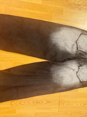 Svarta baggy jeans med drakmönster - Säljer ett par svarta baggy jeans med grått drakmönster på ena benet och cool faded effekt nedtill. Jeansen har fem fickor, bred passform och kontrastsömmar. Perfekta för dig som gillar streetwear och vill sticka ut med unika detaljer.