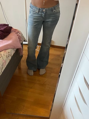 Ljusblå bootcut jeans med låg midja - Säljer ett par ljusblå bootcut jeans med låg midja och klassisk femficksdesign. Jeansen har en lätt tvättad look och vida ben nedtill. Perfekta för en avslappnad och trendig stil.