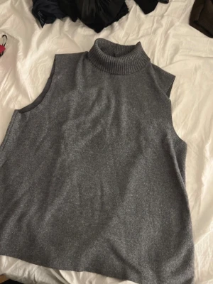 Grå ärmlös polotröja från Zara - Grå ärmlös polotröja i mjukt stickat material. Tröjan har hög polokrage och rak passform. Pris kan diskuteras  