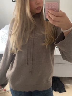 Brun stickad tröja med luva - Mysig brun stickad luva. Tillverkad i mjukt stickat material med ribbade muddar vid ärmslut och nederkant. Perfekt för en avslappnad och chill stil. Inte stickig, använd fåtal gånger och inga tecken på skada osv.