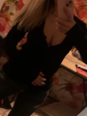 Svart v-ringad långärmad topp - Snygg svart långärmad kofta med djup v-ringning. Perfekt för dig som gillar en enkel men ändå stilren look. Passar till både jeans och kjol och är lätt att matcha med accessoarer.