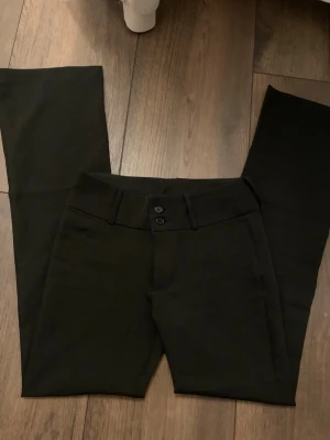 Kostymbyxor - Säljer ett par lågmidjade, utsvängda kostymbyxor. De har fina knapp detaljer på bakfickorna. Säljer eftersom att de inte passar längre. Skriv gärna frågor.💕🫶🏻