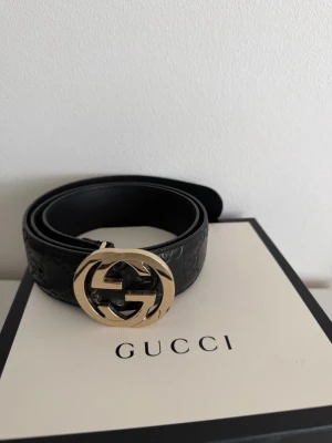 Svart Gucci skärp med GG Spänne - Snyggt svart skärp från Gucci med klassiskt GG-mönster i lädret och ett stort  GG-spänne. Perfekt accessoar för att lyfta vilken outfit som helst. Kommer med originalförpackning och påse.