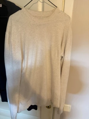 Beige sweatshirt från These Glory Days - En stilren beige sweatshirt från These Glory Days i storlek Large. Tröjan har rund halsringning, långa ärmar och ribbade muddar vid ärmslut och nederkant. Perfekt för en avslappnad och enkel look.