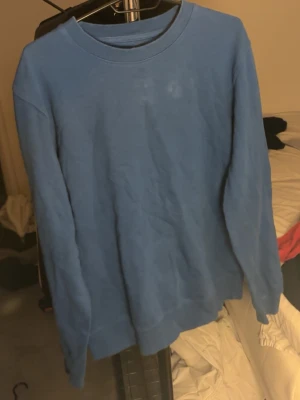 Blå basic sweatshirt - Enkel blå sweatshirt med rund hals och långa ärmar. Tröjan har en avslappnad passform och ribbade muddar vid ärmslut och nederkant. Perfekt för en chill och stilren look.