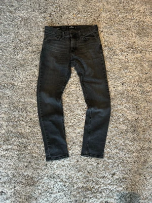 Svarta  jeans från Hollister - Snygga svarta  jeans från Hollister med klassisk femficksmodell och bra passform. Jeansen har normalhög midja och är tillverkade i stretchigt denimtyg för extra komfort. Perfekta för en trendig och avslappnad stil.
