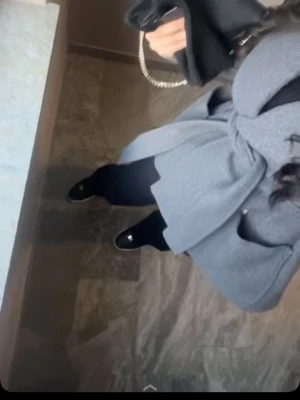 Grå omlottkappa med bälte - Snygg grå kappa med omlottmodell och brett skärp i midjan. Kappan har långa ärmar och bred krage som ger en stilren look. Perfekt för dig som vill ha en klassisk och trendig jacka till höst och vinter.