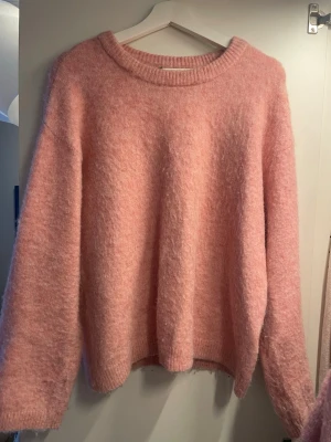 Fluffig rosa stickad tröja - Mysig och oversized stickad tröja i fluffigt rosa material. Tröjan har rund halsringning, långa ärmar och ribbade muddar vid ärmslut och nederkant. Perfekt för lager-på-lager och en chill look.