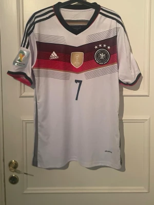 Tyskland hemmatröja 2014 (Schweinsteiger 7) - Äkta Tyskland hemmatröja från VM 2014 med Schweinsteiger 7 på ryggen. Bra skick och snygg detalj med VM-märket på ärmen. Perfekt för samlare eller fotbollsfans. Tveka inte med att höra av er om ni har frågor.