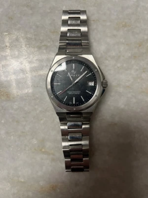 Svart och silver klocka från Tissot - GANT herrklocka i stål – stilren med datum  Säljer en snygg och tidlös herrklocka från GANT.  * Rostfritt stål (boett och länk) * Svart tavla med diskret mönster * Datumvisning * Vattentålig 100 m * Quartz (batteridriven)  Klockan är i bra bruksskick med normalt slitage (små repor finns, se bilder). Fungerar som den ska.  Perfekt som vardagsklocka eller till lite finare tillfällen.