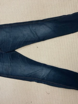 Mörkblå skinny jeans replay - Snygga mörkblå skinny jeans med lätt slitning och tvättade detaljer. Jeansen har klassisk femficksdesign och smal passform som sitter tight längs benen. Perfekta till en avslappnad och trendig look.