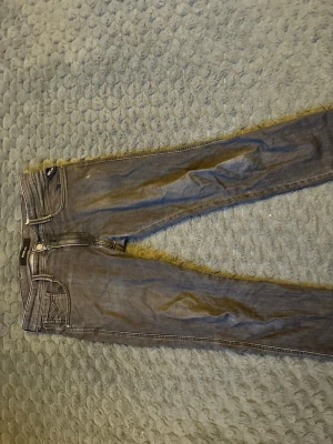 Grå slim fit jeans från replay - Säljer ett par grå slim fit jeans från replay  med klassisk femficksdesign och dragkedjegylf. Jeansen har en snygg tvättad look och smal passform som sitter tajt längs benen. Perfekta för en trendig och avslappnad stil. Kom privat för pris