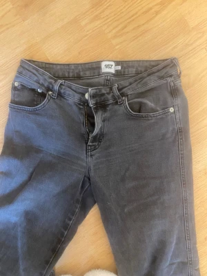 Grå jeans från 157 - Snygga grå jeans från 157 med klassisk femficksmodell och utsvängda ben. Jeansen har knapp- och dragkedjegylf samt silverfärgade nitar. Perfekta för en avslappnad och trendig stil.