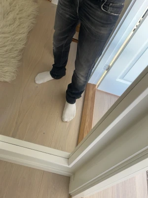 Svarta nudie slim fit jeans  - Säljer ett par svarta slim fit jeans från nudiemed snygga slitningar och tvättade detaljer. Jeansen är o mycket bra skick och passar perfekt till vardags . Längden är 34 och midja 31
