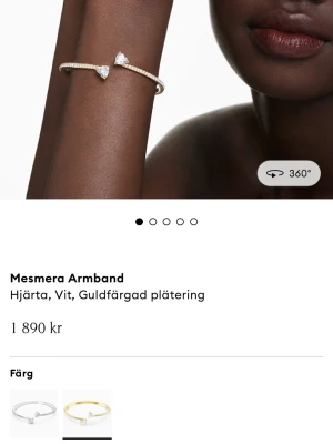 Swarovski Mesmera armband hjärta - Snyggt armband från Swarovski med guldfärgad plätering och två hjärtformade vita Swarovski Zirconia-kristaller. Designen är elegant och smal, perfekt för dig som gillar stilrena accessoarer. Spännet är av typen Wonderklick. Nypris 1890kr