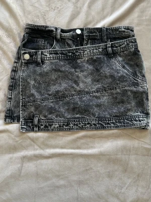 Vintage Y2k jeanskjol - En jätte cool och unik Y2K jeanskjol i grå svart färg med ett främre jeans stycke med knapp (se bild) 💕  Midjemått: Ca 39cm Längd: ca 37cm Nederkant (bredd längst ner): ca 50cm  Alla bud över 250kr accepteras - säg till om du har några frågor :D  018  #vintage #y2k #jeanskjol #sommar #vintagedenim #denim #secondhand #preloved #lowrise #y2kvintage #miniskirt #minikjol