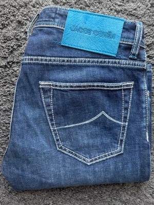 Jacob Cohën Nick - W31 - Nya! - Lyxiga Jacob Cohën jeans i modellen Nick med en fantastisk blå tvätt och exklusiv premiumkänsla.  🧵 JC - Nick  📏 W31 Slim fit  🧩 98% bomull, 2% elastan  📐 Mått: Midja 41cm, Längd 105cm, Benslut 17cm, Lår 28cm  ✅ Skick: 10/10 - Nya och aldrig använda. Prislappen är tyvärr inte kvar, plastlappar på insidan som är kvar från orginalförpackning.   Detaljer: Blå pony hair patch, broderier & citat, logoknappar & italienskt hantverk. Certilogo äktahets-intyg.  💰 Nypris: Ca 4200 kr  ‼️Skickas snabbt‼️