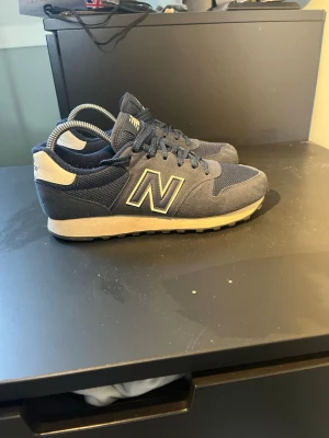 Mörkblå New Balance 500 sneakers - Använda 2 gånger. Nypris 900-1100kr. Kan gå ner i pris vid snabb affär. Snygga mörkblå New Balance 500 sneakers med klassisk N-logga på sidan. Skorna har ovandel i mesh och mocka, vita detaljer vid häl och sula samt mörkblå snörning. Perfekta för en sportig och stilren look.