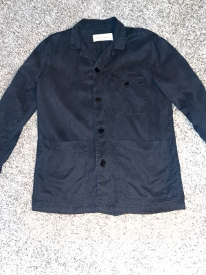 Mörkblå overshirt från A Day's March - Snygg overshirt från A DAY’S MARCH. Overshirten är ganska tunn och är i storlek M men sitter lite åt det oversized hållet. Den är knappt använd. Nypris 1500