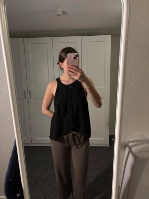 Svart ärmlös linnetopp från Zara - Snygg svart ärmlös linnetopp från Zara med lös passform och rund halsringning. Perfekt för en stilren och enkel look. Toppen är tillverkad i ett lätt och skönt material som känns luftigt.