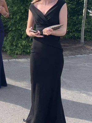 Svart långklänning med v-ringning - Elegant svart långklänning med djup v-ringning och omlottdetalj midjan och upp. Storlek xs🩷jag är 172 och den går ner till marken. ❌den är insydd i svanken  Nypris: 999kr