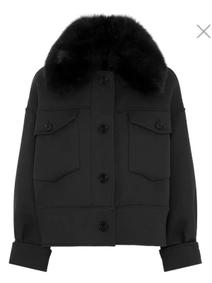 Meotine kappa  - Storlek xs/S använd men fortfarande fint skick. Snygg svart pälsjacka med stor fluffig krage i päls och knappar framtill. Jackan har två bröstfickor med lock och knappar, samt breda muddar med knappdetaljer. Perfekt för kalla vinterdagar och ger en cool look.