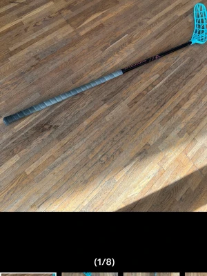 Innebandyklubba med blått blad - Säljer en innebandyklubba med svart skaft och blått plastblad. Greppet är lindat med grå tejp och klubban har en smal, lång form. Perfekt för dig som vill spela innebandy eller träna teknik.