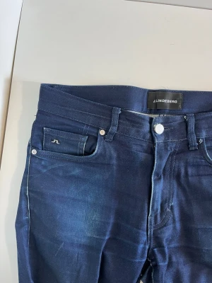 Mörkblå jeans från J.Lindeberg - Snygga mörkblå jeans från J.Lindeberg med klassisk femficksdesign och diskret logga på myntfickan. Hör gärna av dig vid frågor!