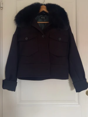 Svart pälsjacka från Meotine XS/S - Stilren svart pälsjacka från Meotine med stor fluffig krage i fuskpäls. Jackan har två stora bröstfickor med lock och knappar samt uppvikta ärmslut. Endast använd 1 gång och kommer som ny! Nypris: 3 200