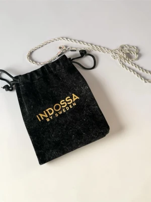 Silverpläterat halsband från Indossa - Säljer ett stilrent halsband i silverfärg med tvinnad kedja. Halsbandet har en enkel och clean design som passar perfekt till många olika outfits. Materialet är metall och kedjan har en snygg glansig finish. Skriv privat om ni vill ha fler bilder