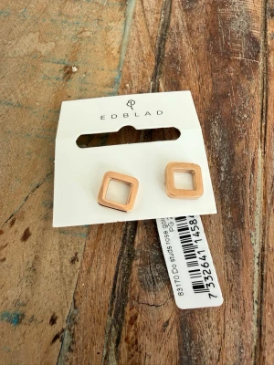 Fyrkantiga örhängen från Edblad - Snygga örhängen från Edblad i modern fyrkantig design. Ett par i roséguld och ett par i svart med roséguldsdetaljer. Tillverkade i metall med stilren, öppen form som ger en trendig look. Helt nya 