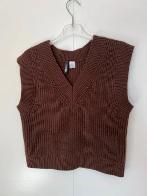 Stickad brun väst från H&M – Stl XS - Klassisk stickad väst i en snygg chokladbrun färg från H&M:s Divided-kollektion. Västen har en djup V-ringning och ribbstickade kanter vid hals, ärmar och nederkant. Perfekt att bära över en skjorta eller t-shirt för en trendig lager-på-lager-look! • Märke: H&M Divided • Storlek: XS • Färg: Brun • Material: 100% akryl • Skick: Sparsamt använd och i mycket fint skick. Övrig info: • 🚭 Rökfritt hem • 🐾 Djurfritt hem Kika på mina andra annonser för att samfrakta 