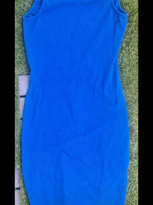 Blå ärmlös kortklänning - En enkel blå ärmlös bodycon klänning i kort modell. Klänningen har en rund halsringning, öppen rygg och är figurnära i passformen. Storlek XS, sparsamt använd