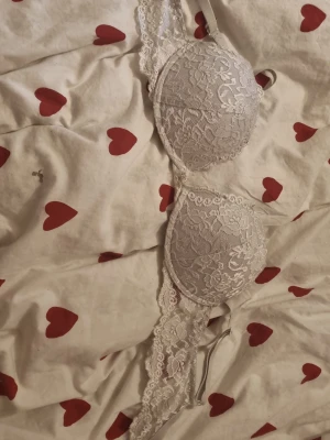 Vit spets-bh med vadderade kupor - Säljer en vit bh med vacker spets och vadderade kupor. Bh:n saknas bygel och breda spetsband som ger en romantisk känsla. Perfekt för dig som gillar feminina detaljer och mjuka material.