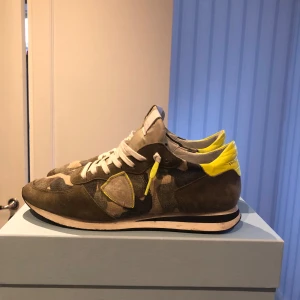 Camouflage sneakers från Philippe Model - Snygga sneakers i camouflage från Philippe Model med gula detaljer och vita snören. Perfekta för en trendig look. Cond 9/10 inget fel på de. Allt oh följer med, fråga gärna i dm om nåt kommer till tanke! Obs ingen retur 