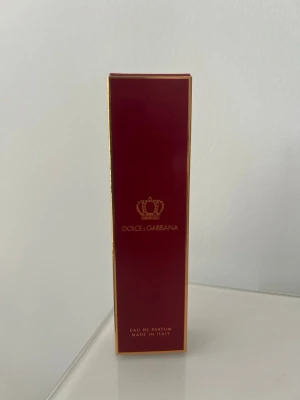 Dolce & Gabbana Q Eau de Parfum - Lyxig parfym från Dolce & Gabbana i elegant glasflaska med guldlock. Doften är Q Eau de Parfum och kommer i en snygg röd och guld kartong. Flaskan har en ljusrosa vätska och minimalistisk design med krona och logga på framsidan. Parfymen är testad. Se volymen på bild 2. 