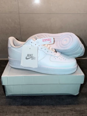 Nike Air Force 1 vita sneakers - Klassiska helvita Nike Air Force 1 sneakers i lågt utförande. Skorna har ovandel i slätt läder, perforerad tåbox för ventilation och vit yttersula med ikoniskt cirkelmönster. Tidlös design med Nike-logga på sidan och tunga. Perfekta för en clean och stilren look.priset kan diskuteras 