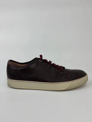 Vinröda Lanvin sneakers i läder - Snygga vinröda sneakers i läder med matchande vinröda skosnören och vit sula. Klassisk låg modell med stilren design som passar till det mesta. Perfekta för dig som vill ha en clean och tidlös look.
